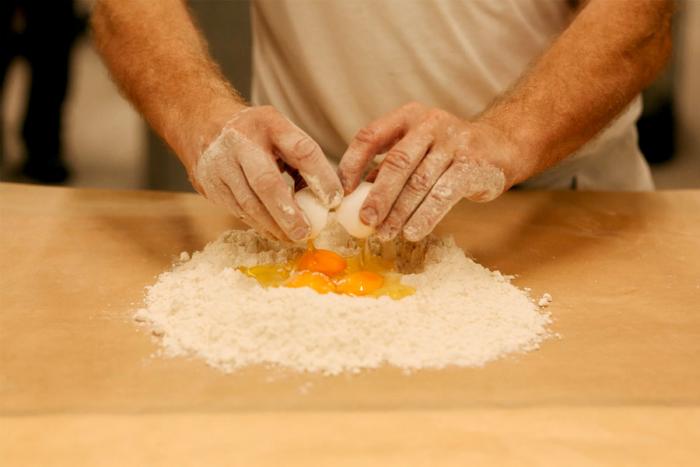Ein Bäcker schlägt ein Ei in Mehl
